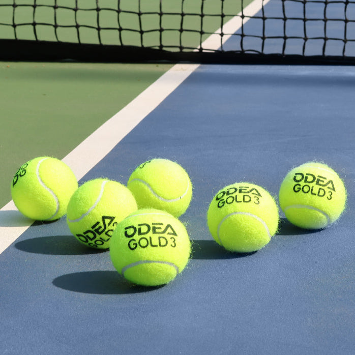 Yellow tennis balls with branding on a blue tennis court.